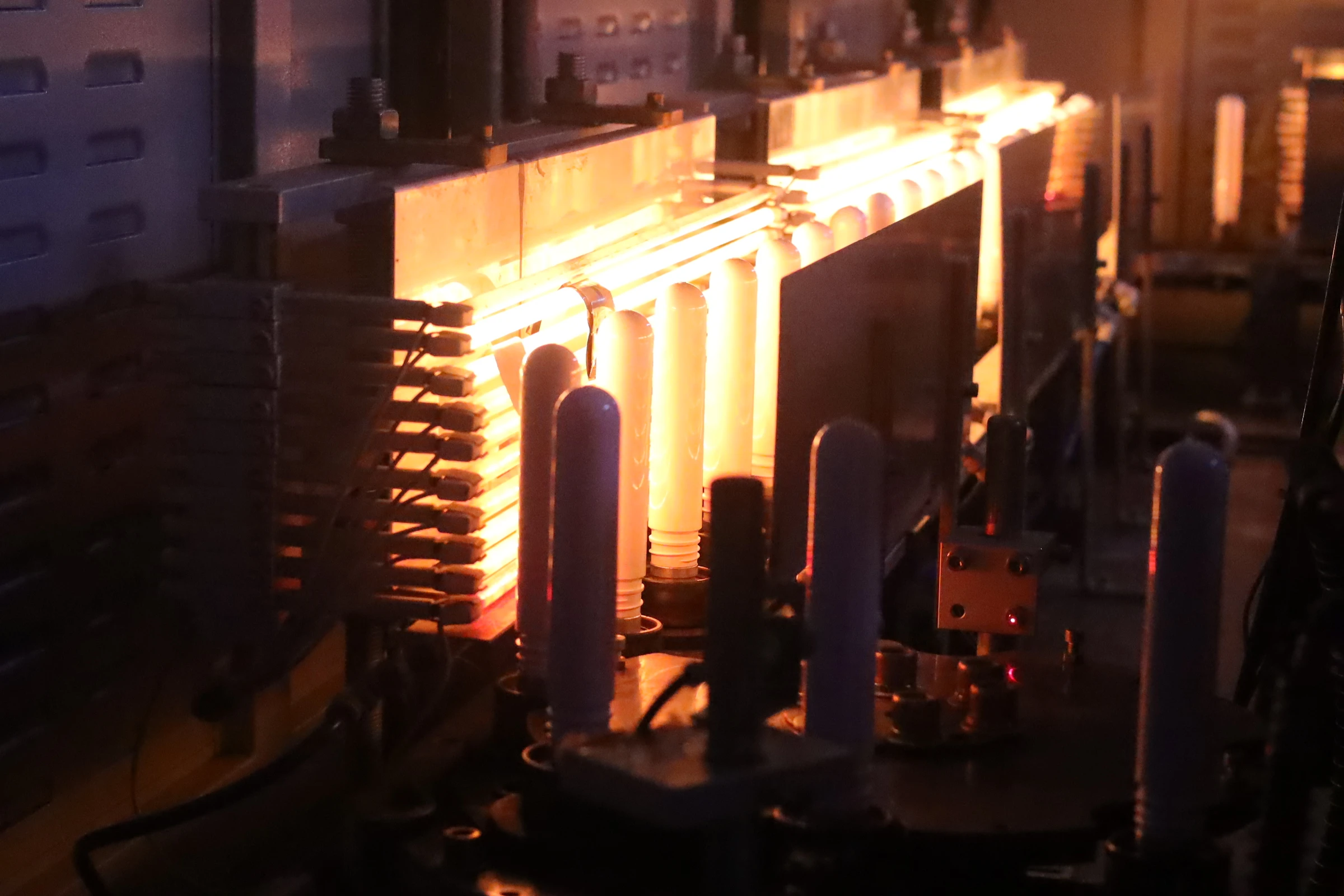 Bottle forms at a heated production station